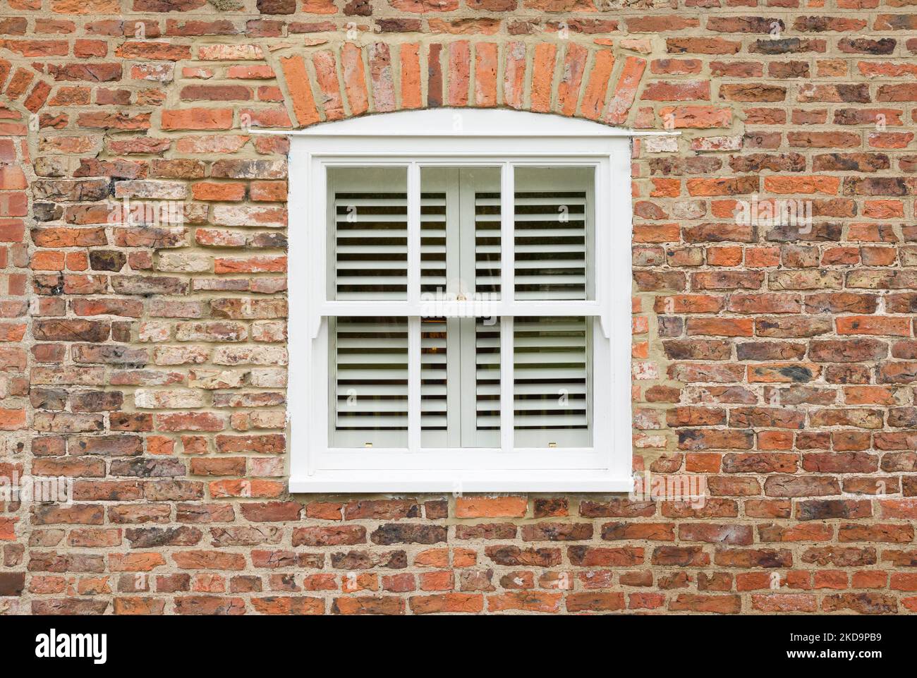 Exterior of old brick house with wooden sash window and wooden blinds, England, UK Stock Photo