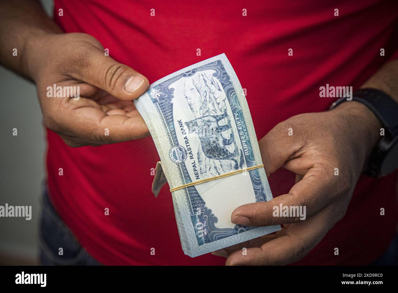 Closeup at a pack of 50 Nepalese Rupees while a man behind the counter