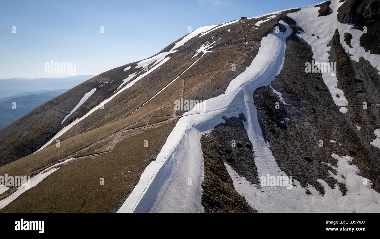 A drone view of snow in Campo Imperatore in the Gran Sasso and Laga Mountains National Park, on May 13, 2022. -Gran Sasso d'Italia is a massif in the Apennine Mountains of Italy. Its highest peak, Corno Grande (2,912 metres), is the highest mountain in the Apennines, and the second-highest mountain in Italy outside the Alps. (Photo by Manuel Romano/NurPhoto) Stock Photo