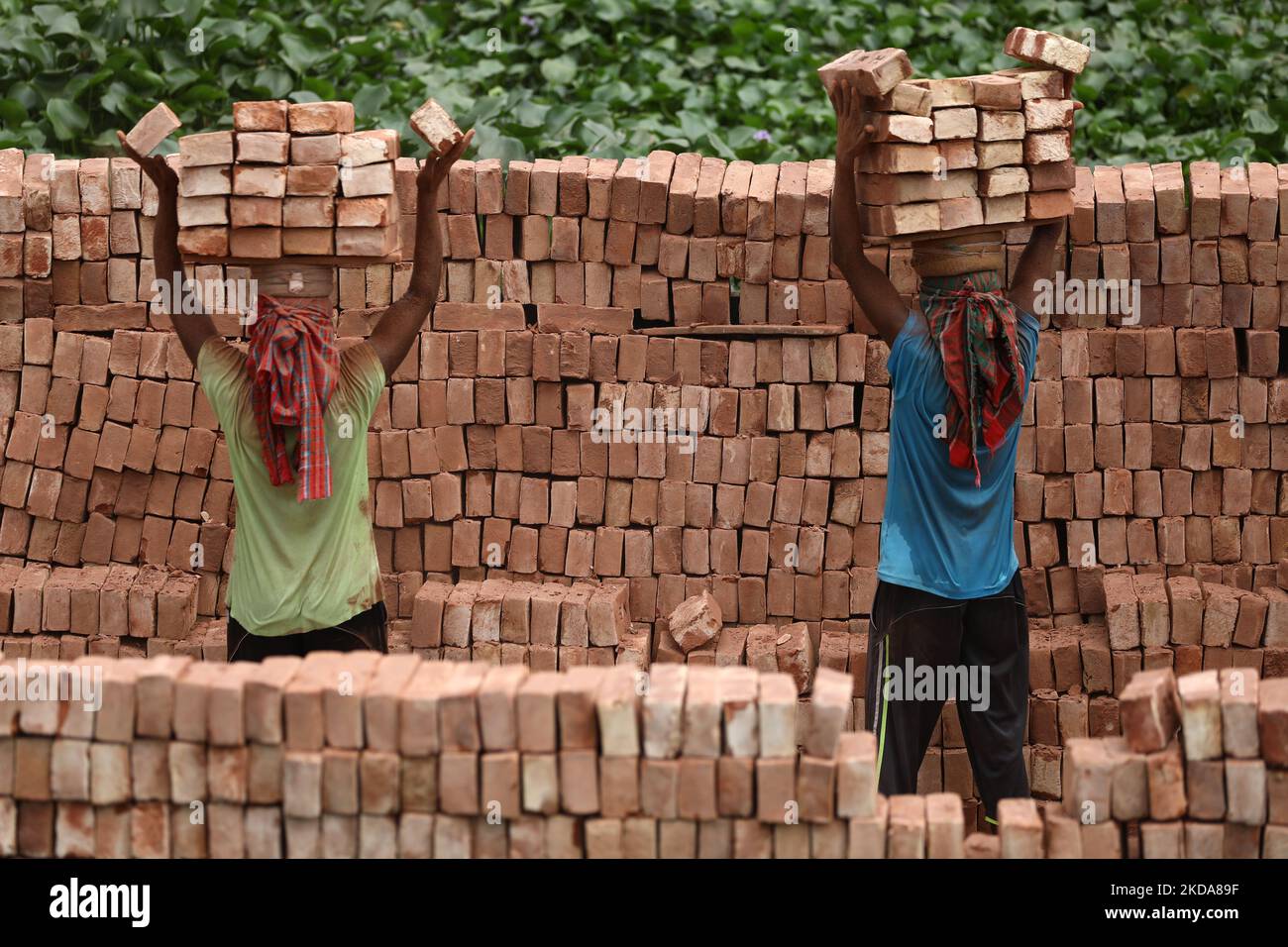 Laborers unload bricks from a cargo ship at the Kamrangirchar area in ...