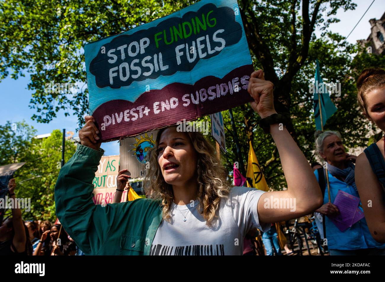 A woman is holding a placard against fossil fuels, during the ...