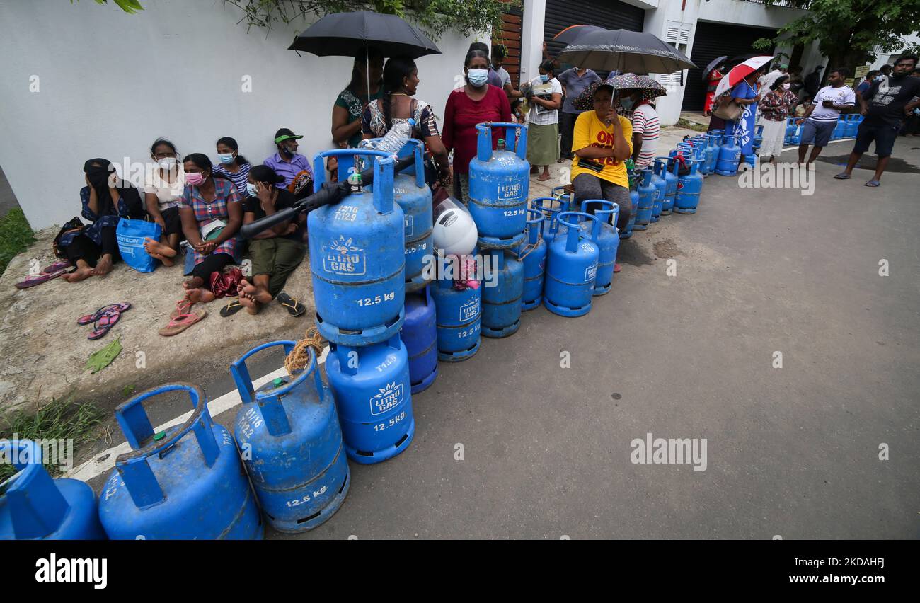 Sri Lankans wait in line with empty cooking gas cylinders near a gas