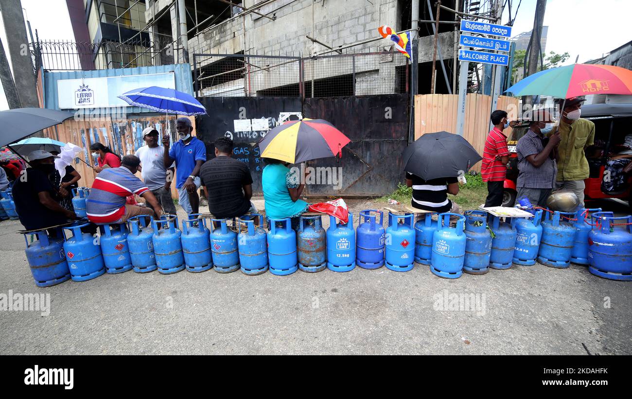 Sri Lankans wait in line with empty cooking gas cylinders near a gas