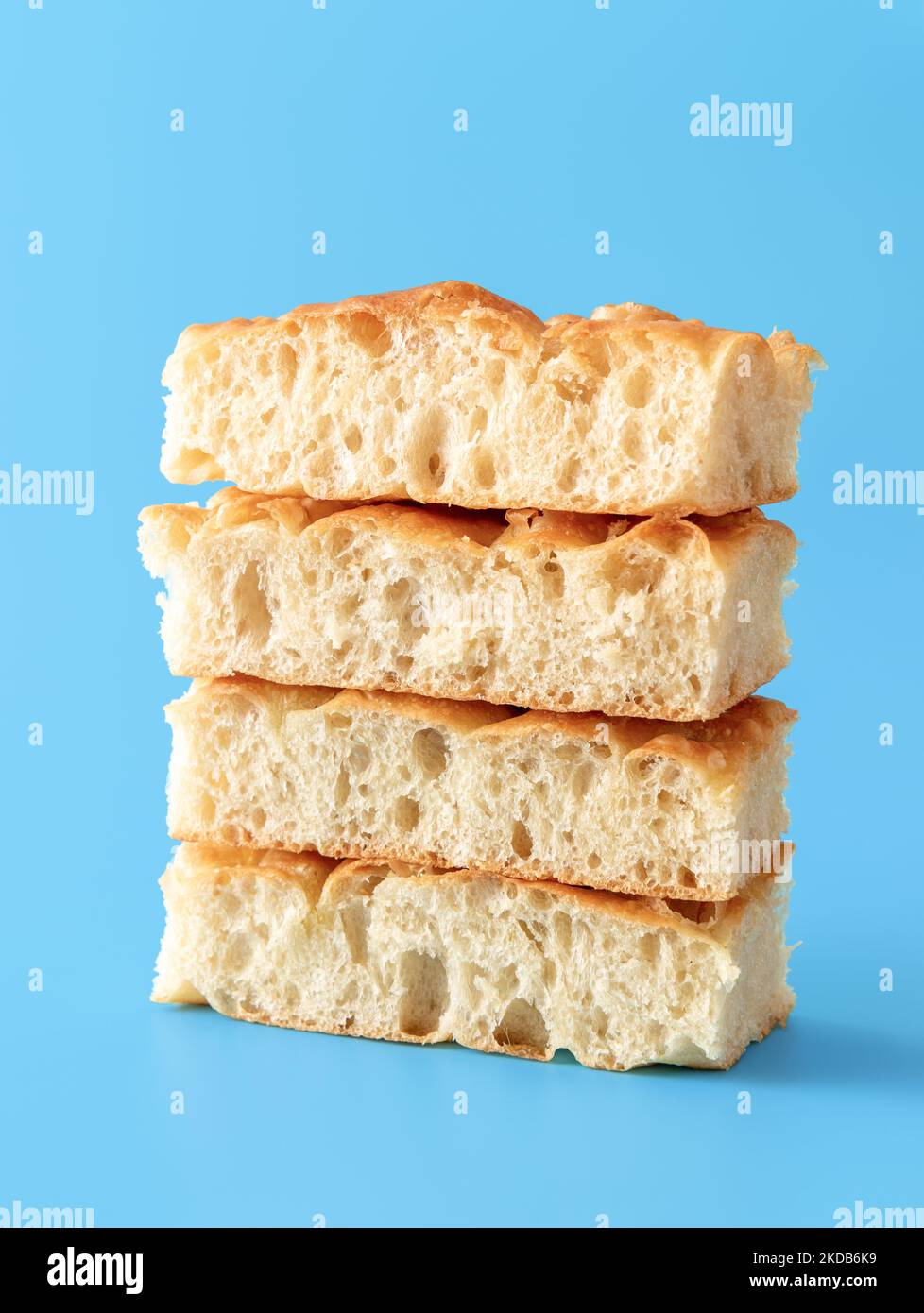 Stack of focaccia bread slices on a blue table. Pieces of homemade focaccia minimalist on a blue background. Stock Photo
