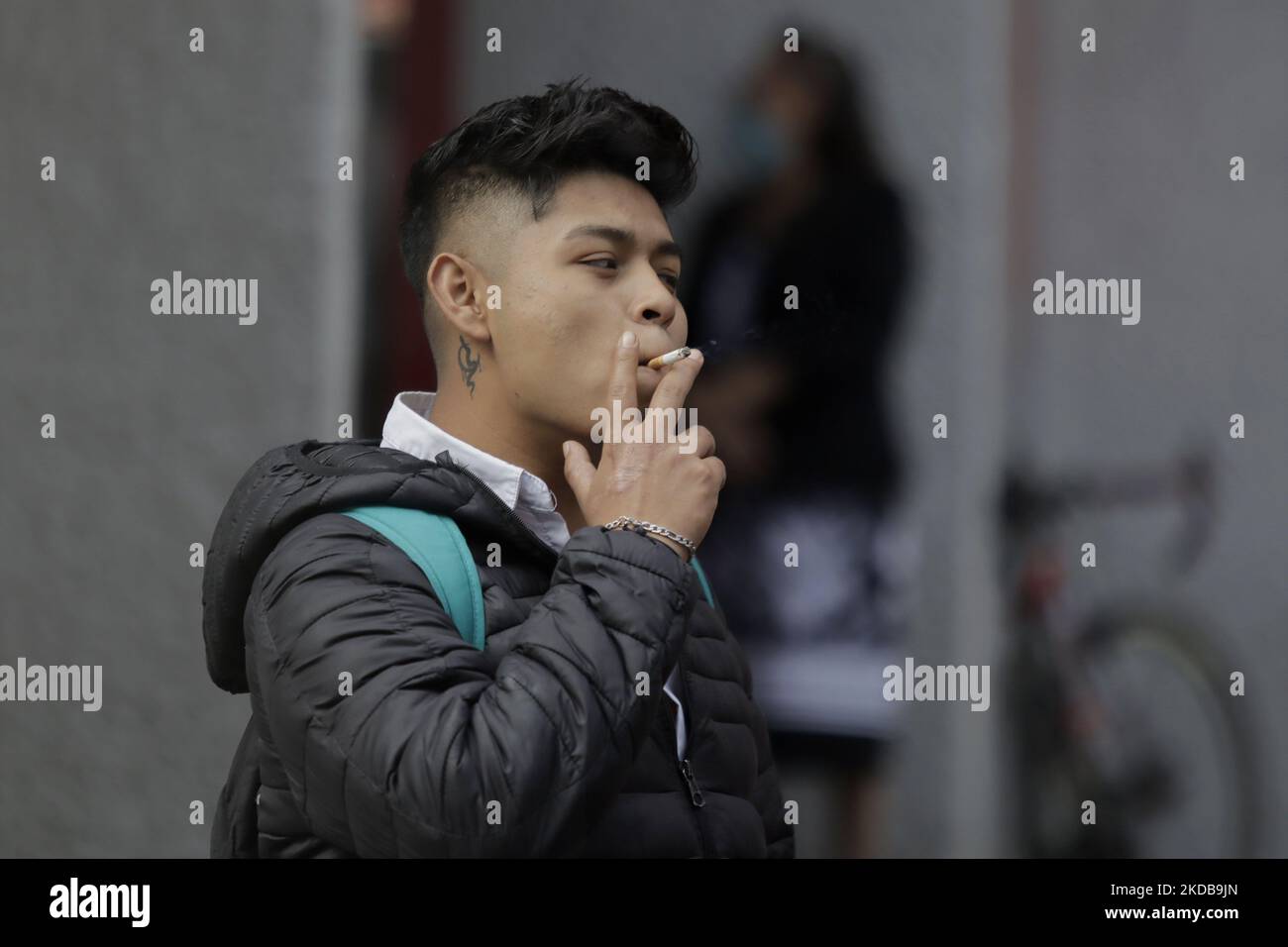 A young man smoking a cigarette in the streets of Mexico City during