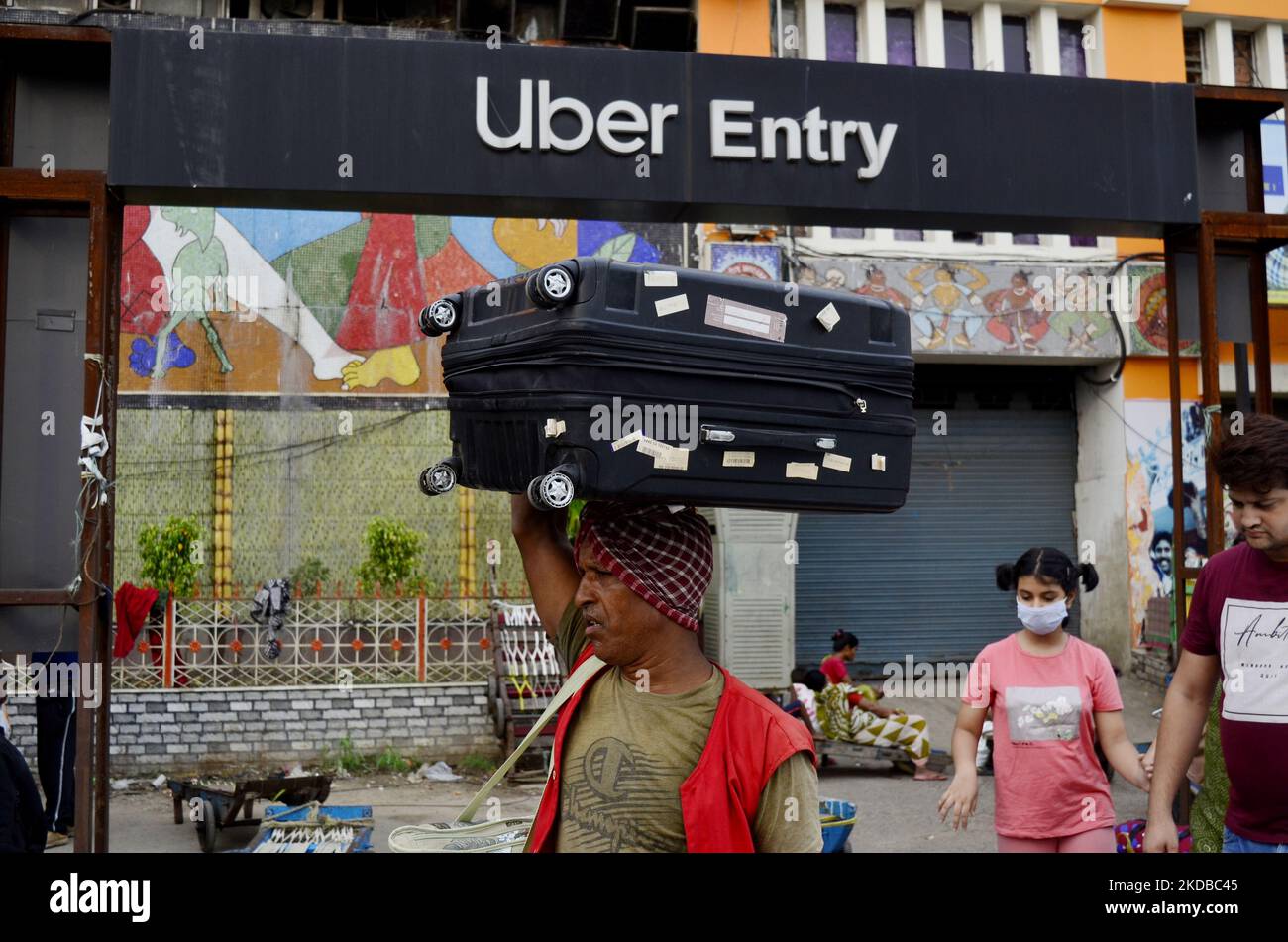 A railway coolie carries luggage on his head near a railway station in