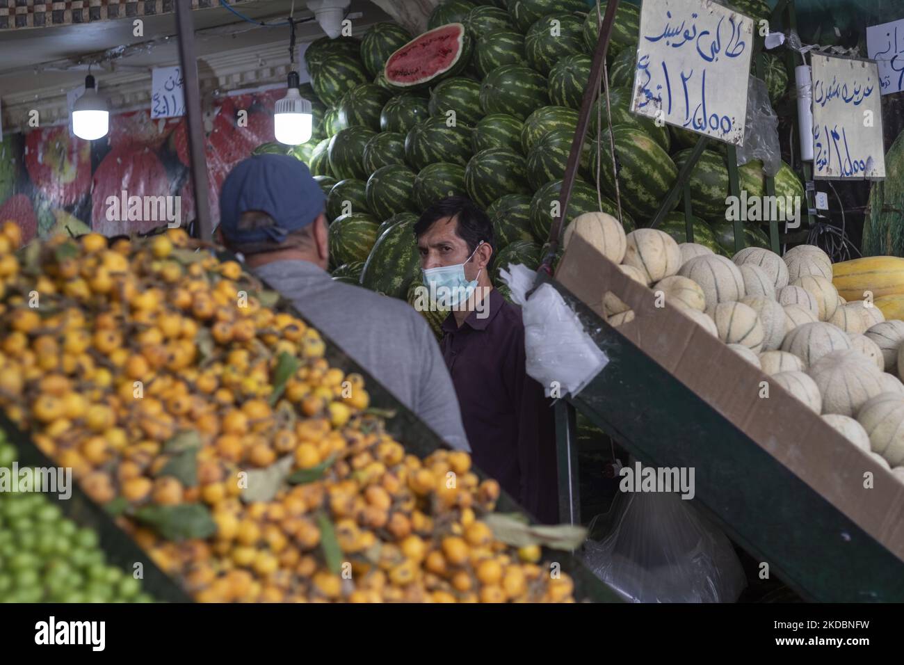 An Iranian fruiterer (R) talks to a client at a fruit shop at the ...