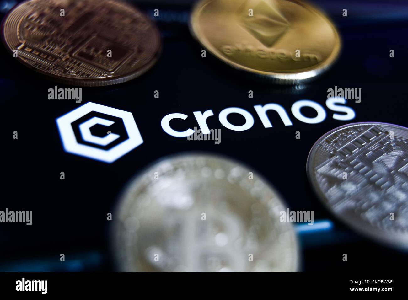 Cronos logo on a smartphone screen with crypto symbols in the background