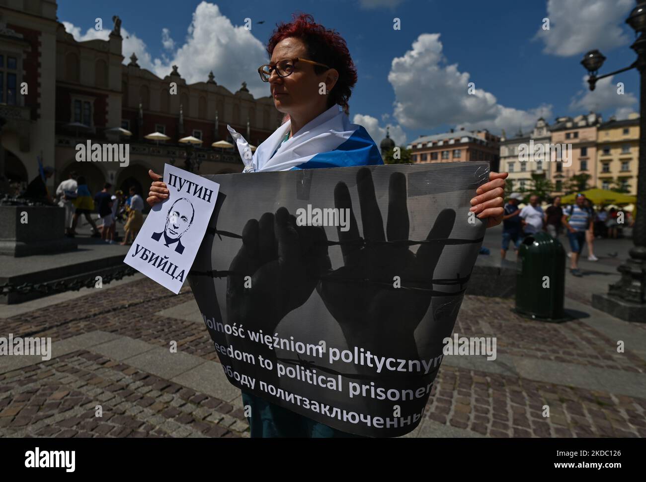 A protester holds a placard with words 'Putin Killer' and a poster 'Freedom to political prisoners'. Members of the local Russian diaspora in Krakow join the global anti-war demonstration of all free Russians and protest against the war with Ukraine at the Adam Mickiewicz monument in the Main Square in Krakow. On Sunday, June 12, 2022, in Krakow, Poland. (Photo by Artur Widak/NurPhoto) Stock Photo