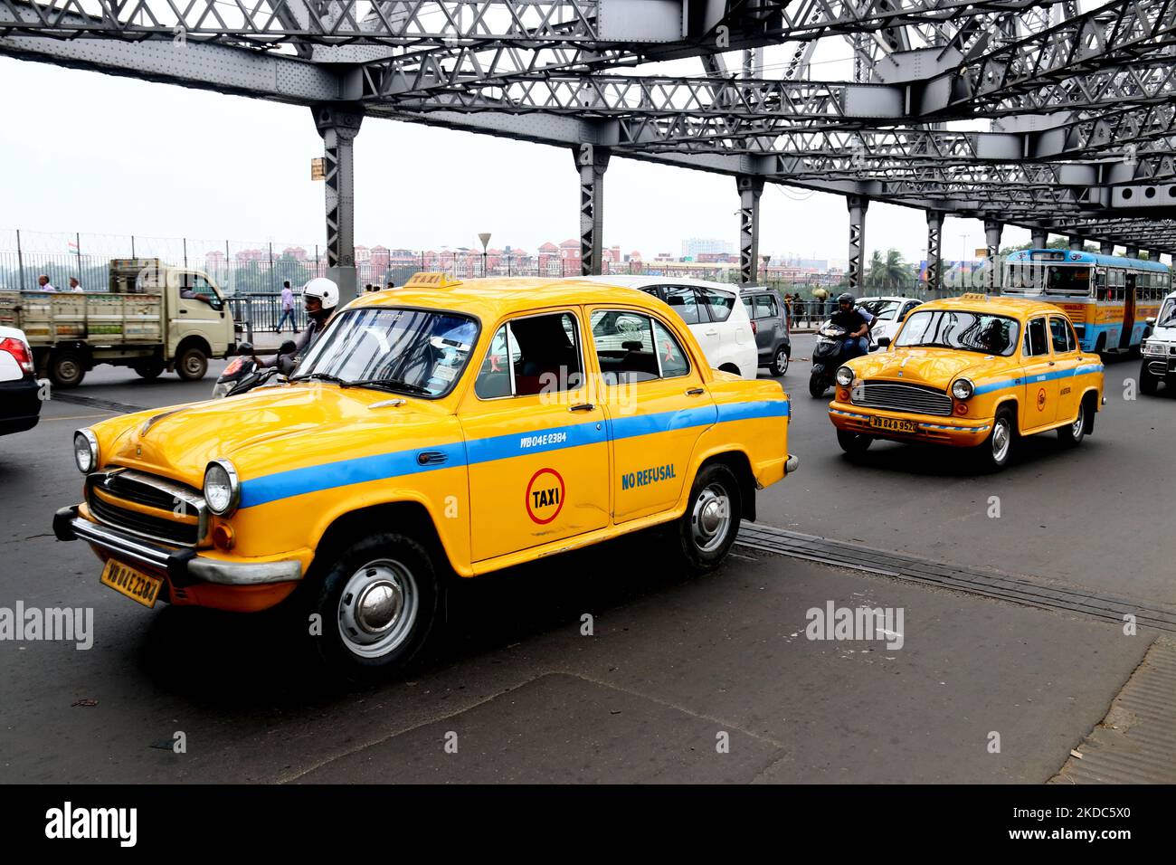 A Yellow Ambassador two taxi past the Howrah Bridge in Kolkata on June 16,2022.The Ambassador car of Hindustan Motors, which once ruled the Indian streets, will now be seen on Indian roads in a new form.Hindustan Motors Limited sold the Ambassadorâ€™s name to Peugeot for Rs 80 crore, which included the brand and rights. It is said that the two will work together to bring the car back to a new look. (Photo by Debajyoti Chakraborty/NurPhoto) Stock Photo
