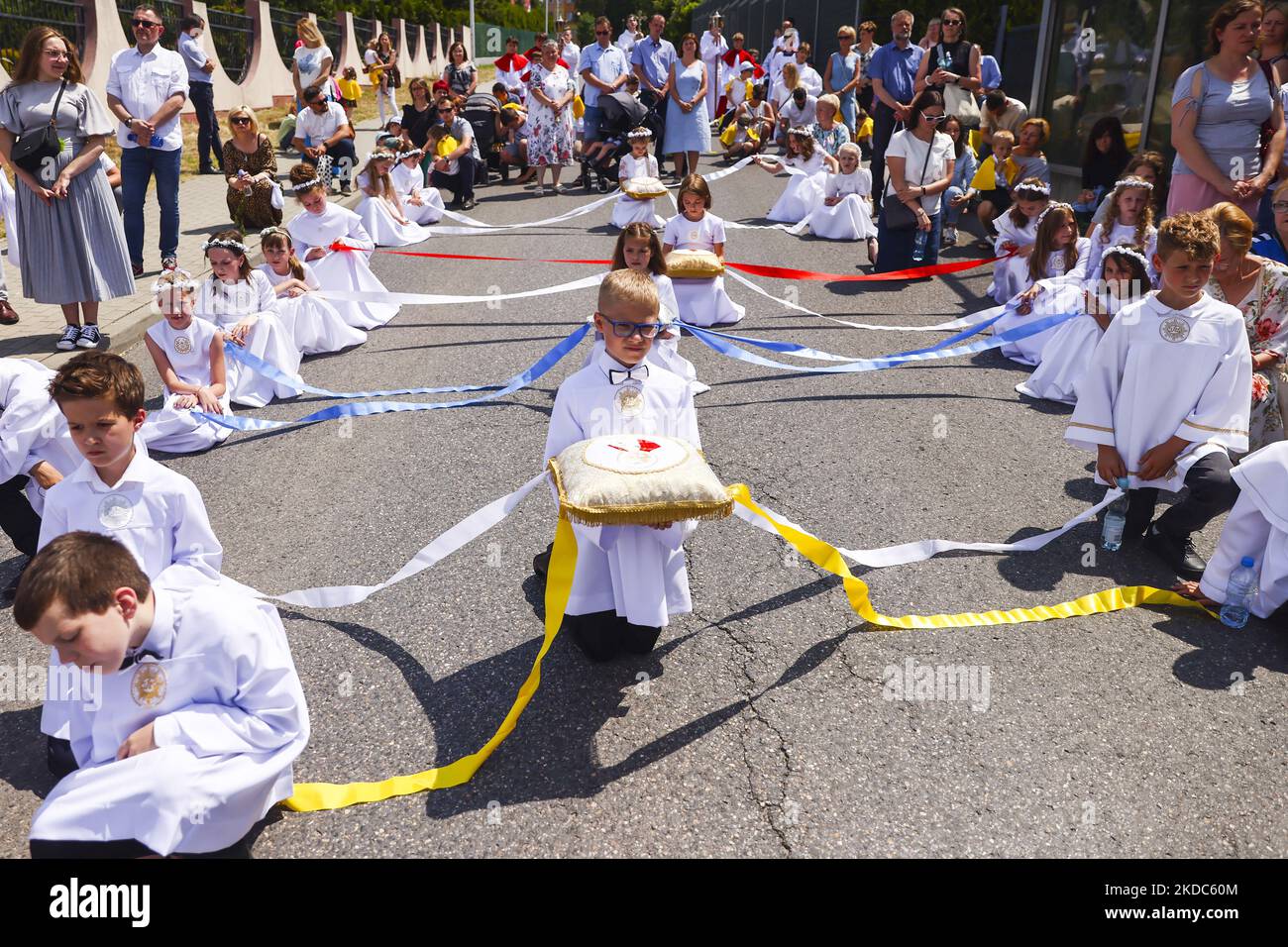 Children attend Corpus Christi procession in Andrychow, Poland on June 16, 2022. The procession starts with a priest carrying a monstrance under a canopy. The faithful follow him singing religious hymns, while young girls dressed in white or traditional regional dresses scatter flower petals along the route. Corpus Christi is a Catholic moveable feast commemorating the Transubstitution. (Photo by Beata Zawrzel/NurPhoto) Stock Photo