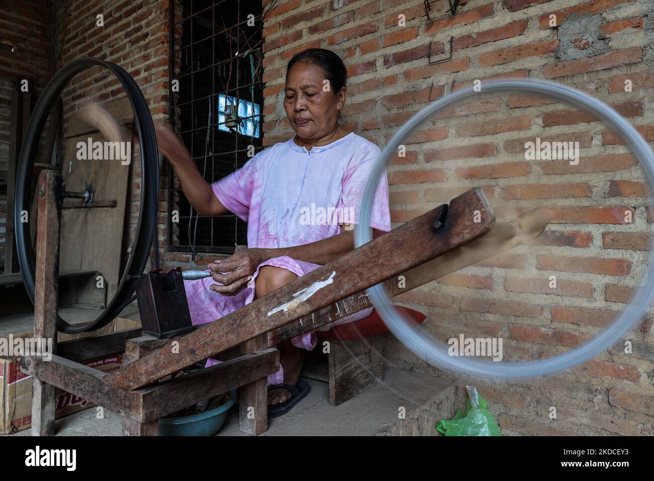 A woman working with handmade wooden frames for spinning thread at the traditional weaving