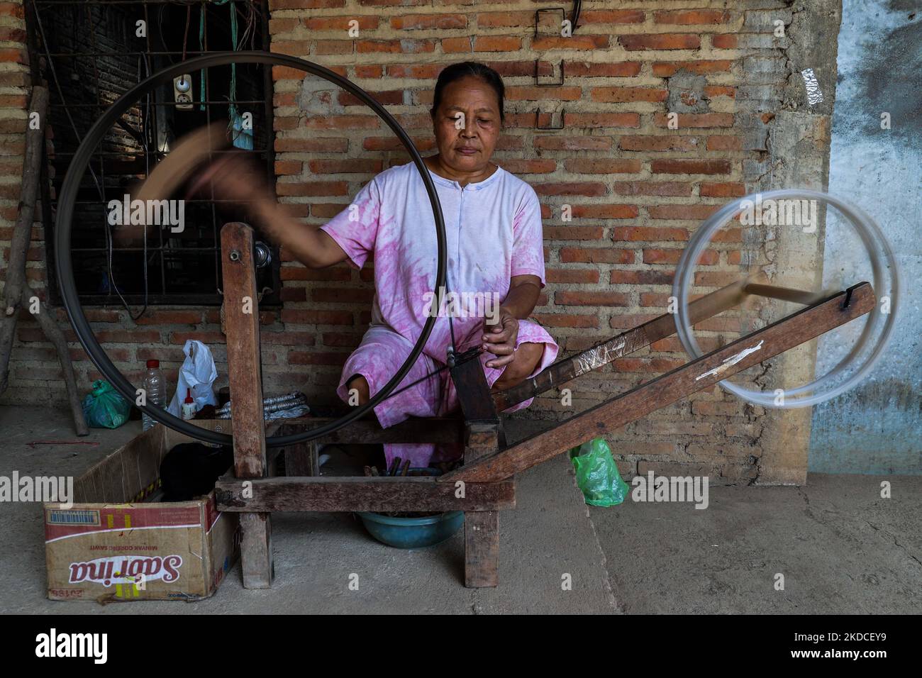 A woman working with handmade wooden frames for spinning thread at the traditional weaving