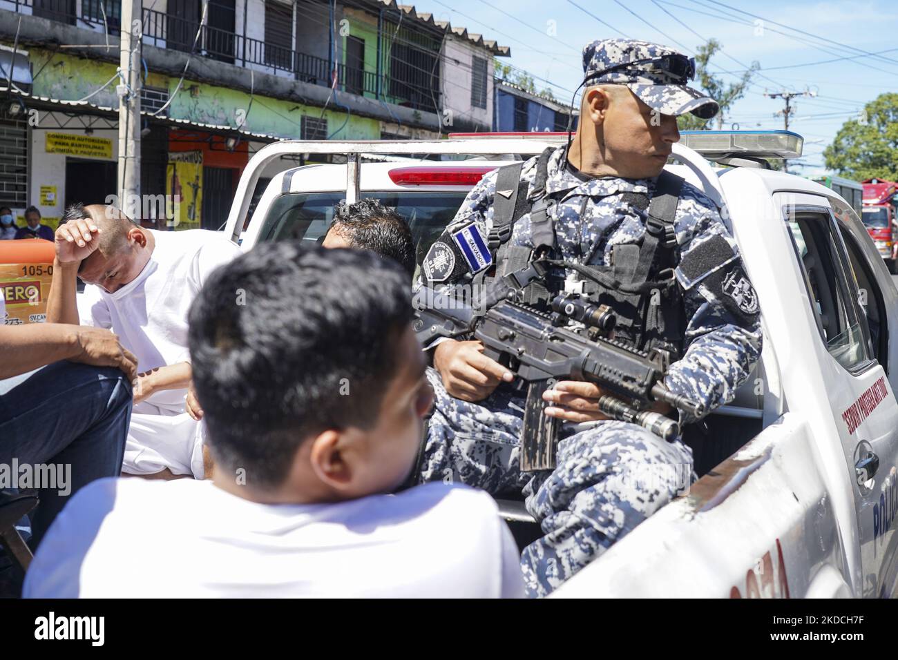 A police officer escorts alleged gang members into a detention center on June 22, 2022 in San Salvador, El Salvador. The Salvadoran government through the Salvadoran Congress extended a state of emergency put in place to hit gang structures for the fourth month in a row as the government reports more than 41,000 alleged gang members captured (Photo by Camilo Freedman/NurPhoto) Stock Photo