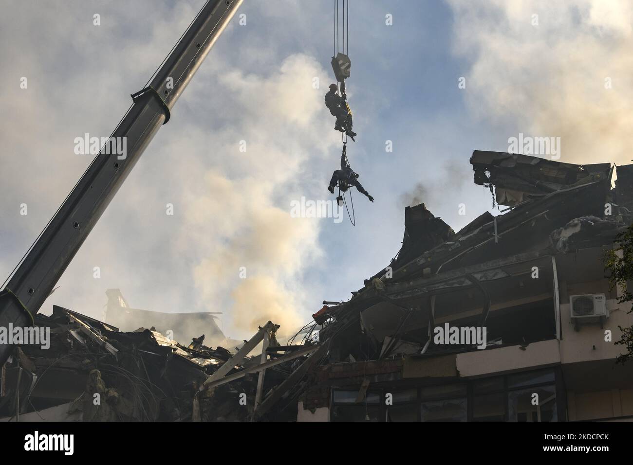 Rescuers elevated by a crane at an apartment building destroyed in a ...