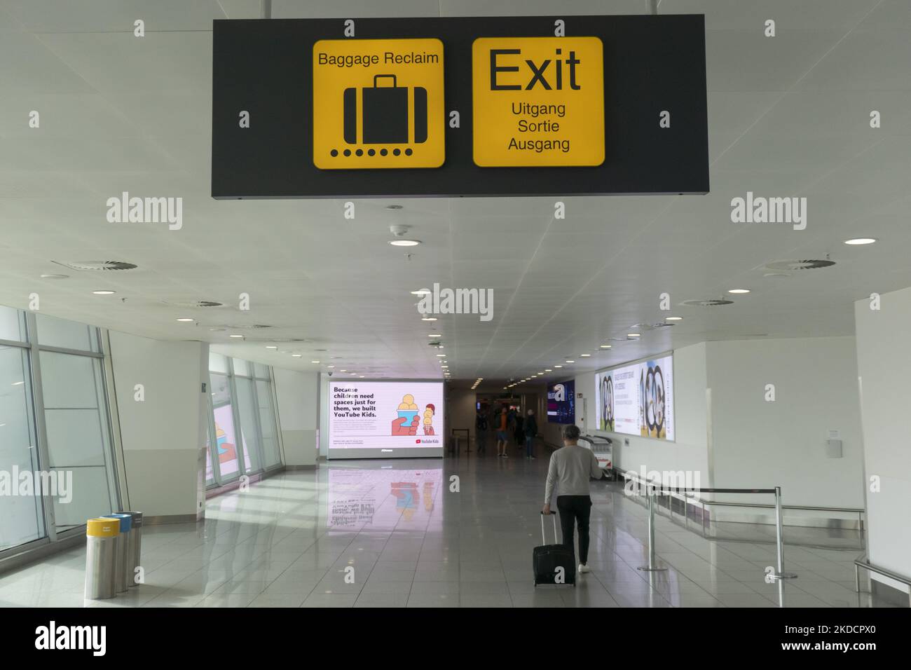 Luggage and Exit signs. Morning departing and arriving passengers are seen carrying their