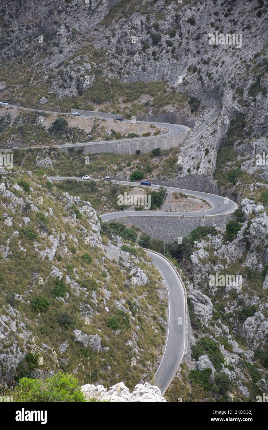 A vertical shot of a wavy road leading through the rocky mountain, with