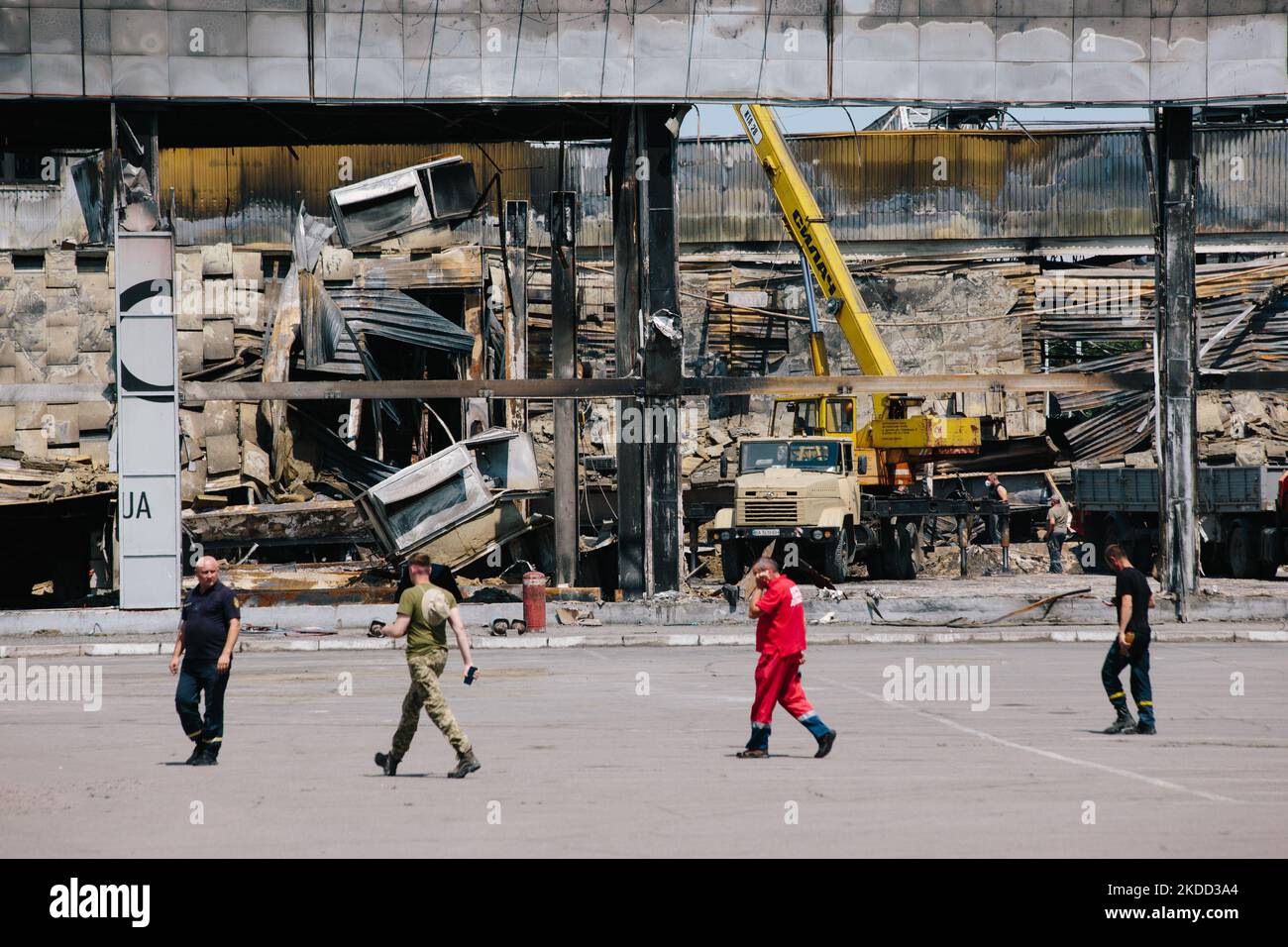 Firefighters, military and medical worker on the backdrop of an attacked mall in the center of Kremenchuk, Ukraine, on June 30, 2022 after the russian shelling. More than 20 people were killed, and more than 30 missing (Photo by Pavlo Pakhomenko/NurPhoto) Stock Photo
