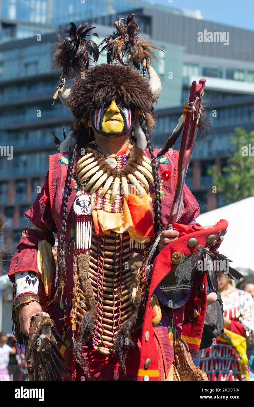 Toronto, ON, Canada - June 18, 2022: Eagle Staff Carrier Bernard Nelson (yellow face) stands in front of the crowd. In honour of National Aboriginal Day, the Na-Me-Res Traditional Outdoor Pow Wow was held at Fort York. The festival celebrates Indigenous and Metis culture through traditional and contemporary music, educational programming, storytelling, dance, theatre, and food (Photo by Anatoliy Cherkasov/NurPhoto) Stock Photo