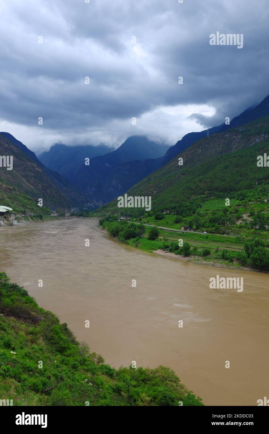 A vertical of a river flowing through the mountains under a cloudy sky ...