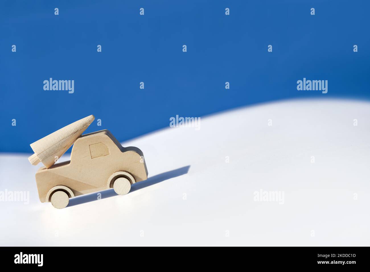 Wooden toy, silhouette of Christmas tree on toy car on colored layered paper background. Xmas holiday blue celebration background. Copy-space, place Stock Photo