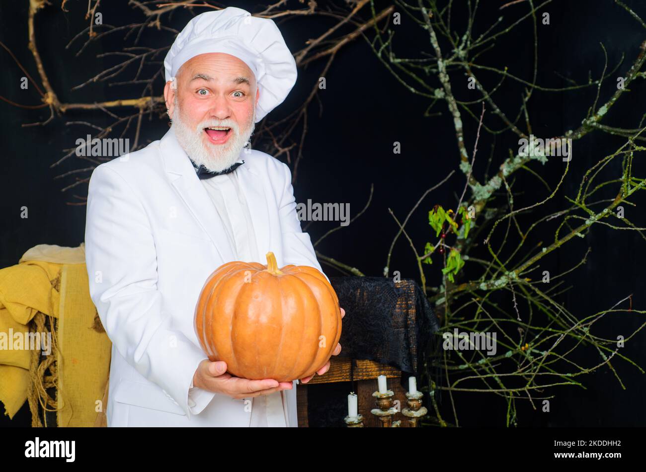 Harvest pumpkin. Bearded cook in chef hat with pumpkin. Farm market. Autumn vegetables. Diet food. Stock Photo
