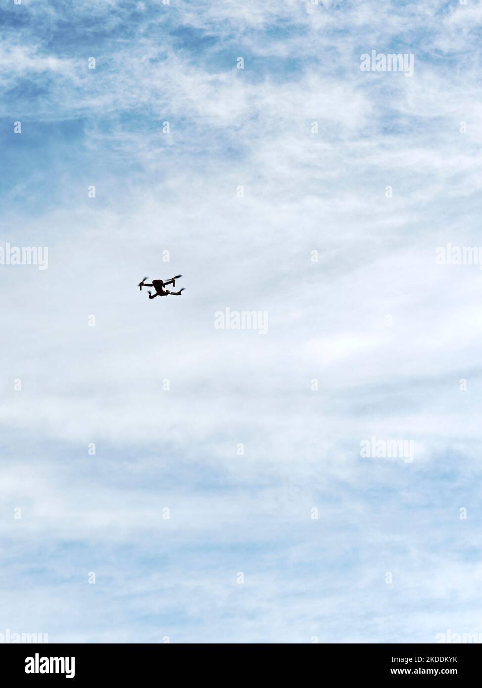 Small four blade flying drone being flown in an empty sky. Stock Photo