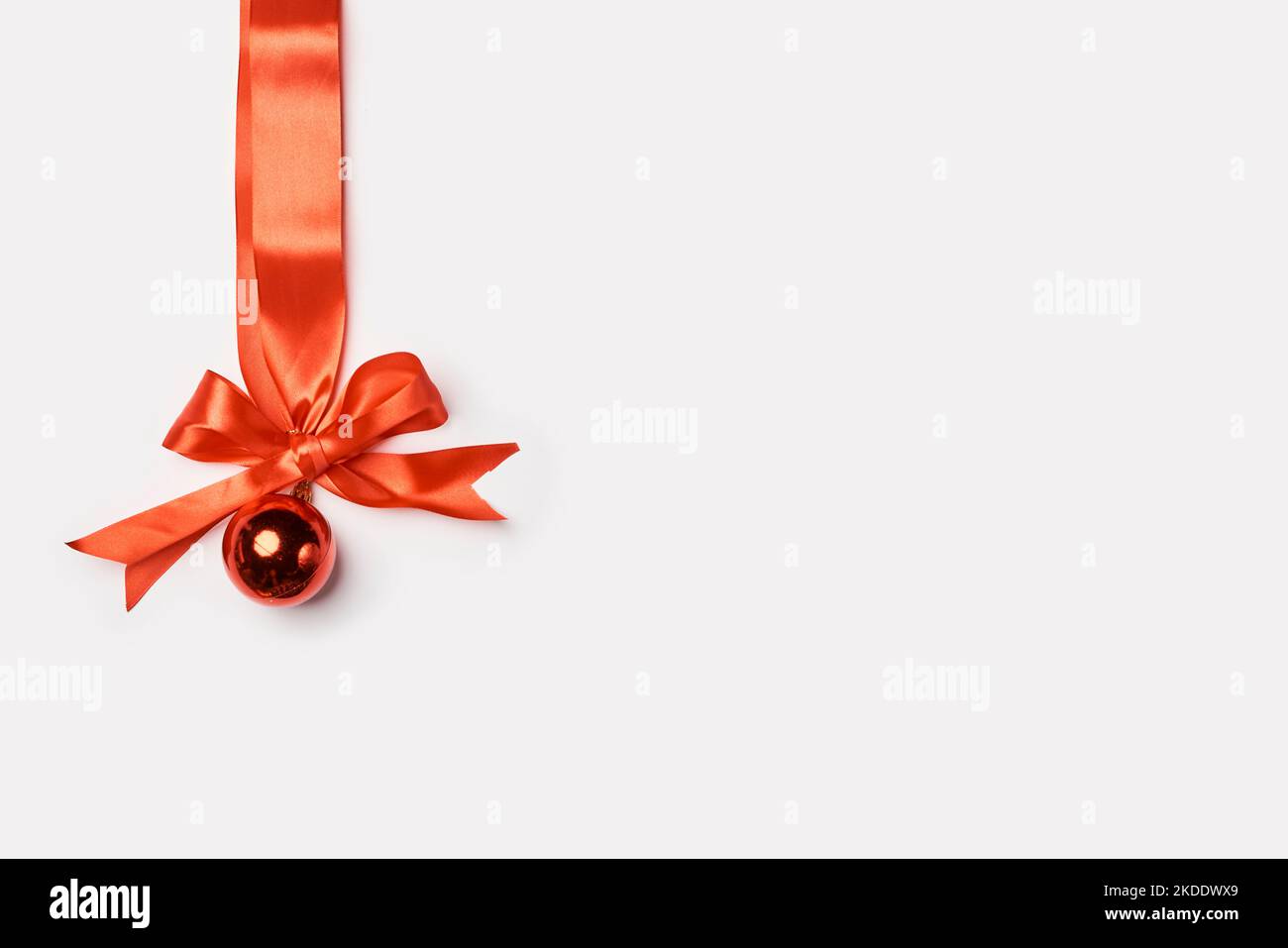 a christmas orname with a red ribbon and a golden bell on it's side ...