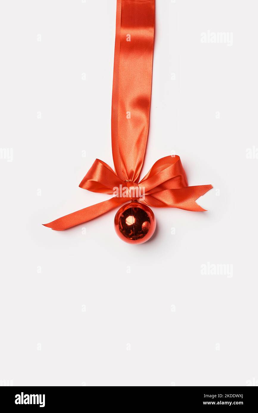 a christmas orname with a red ribbon and a golden ball on it's side ...