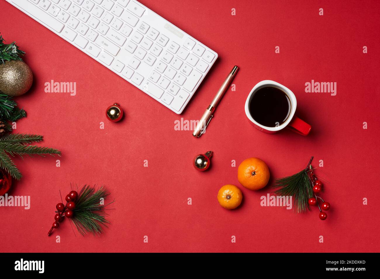 an office desk with a keyboard, oranges and christmas decorations on the table next to it is a cup of coffee Stock Photo
