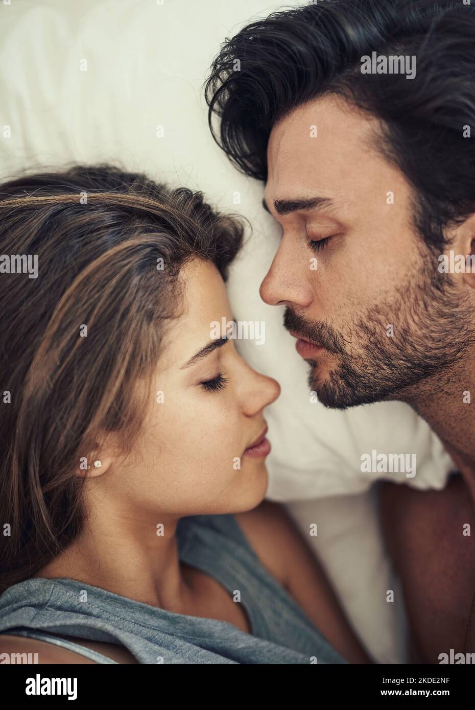 Making sure they wake up to one another. High angle shot of an affectionate young couple sleeping in their bed. Stock Photo