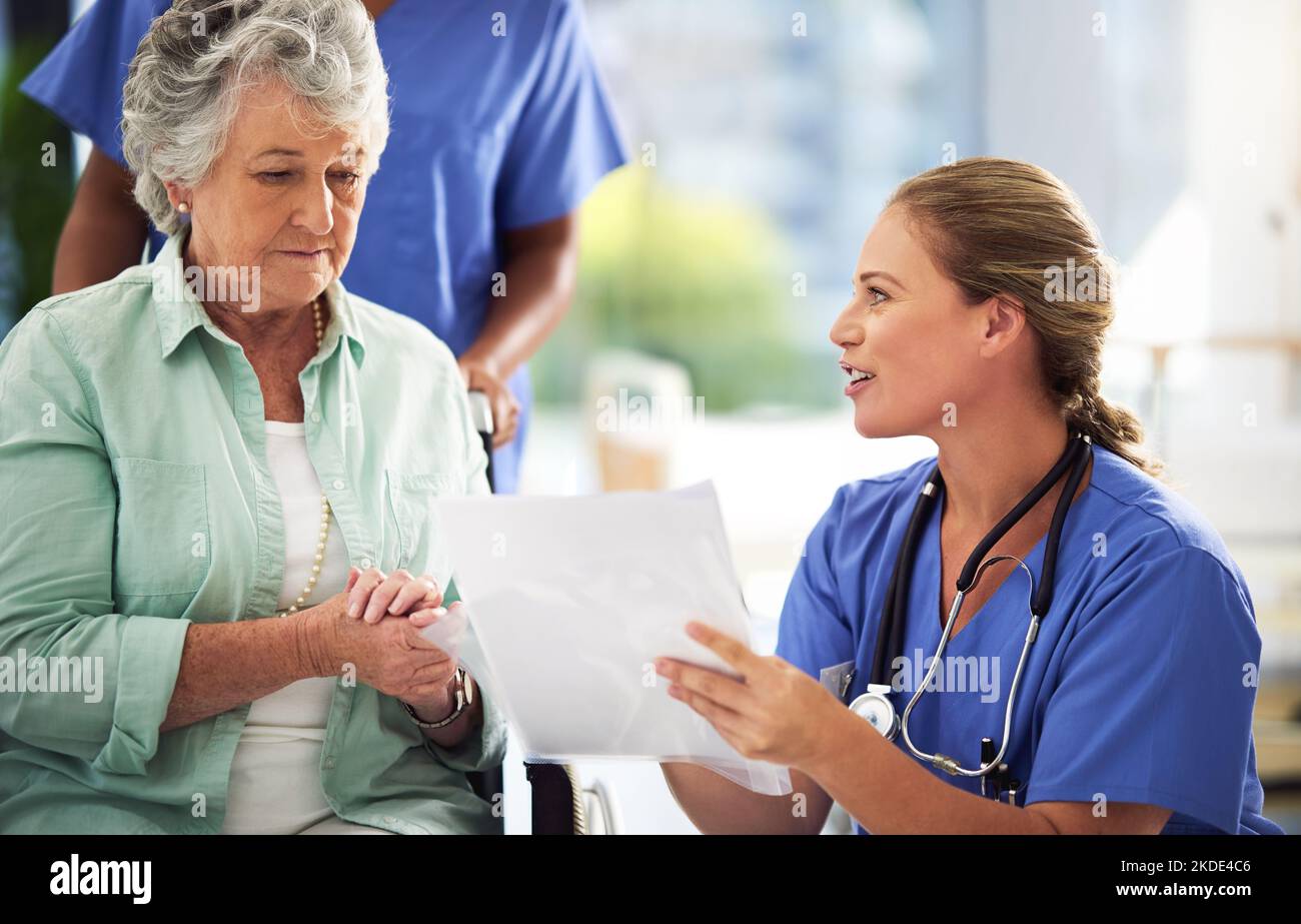 Talking through possible treatments. a doctor discussing treatments with a senior woman sitting in wheelchair in a hospital. Stock Photo