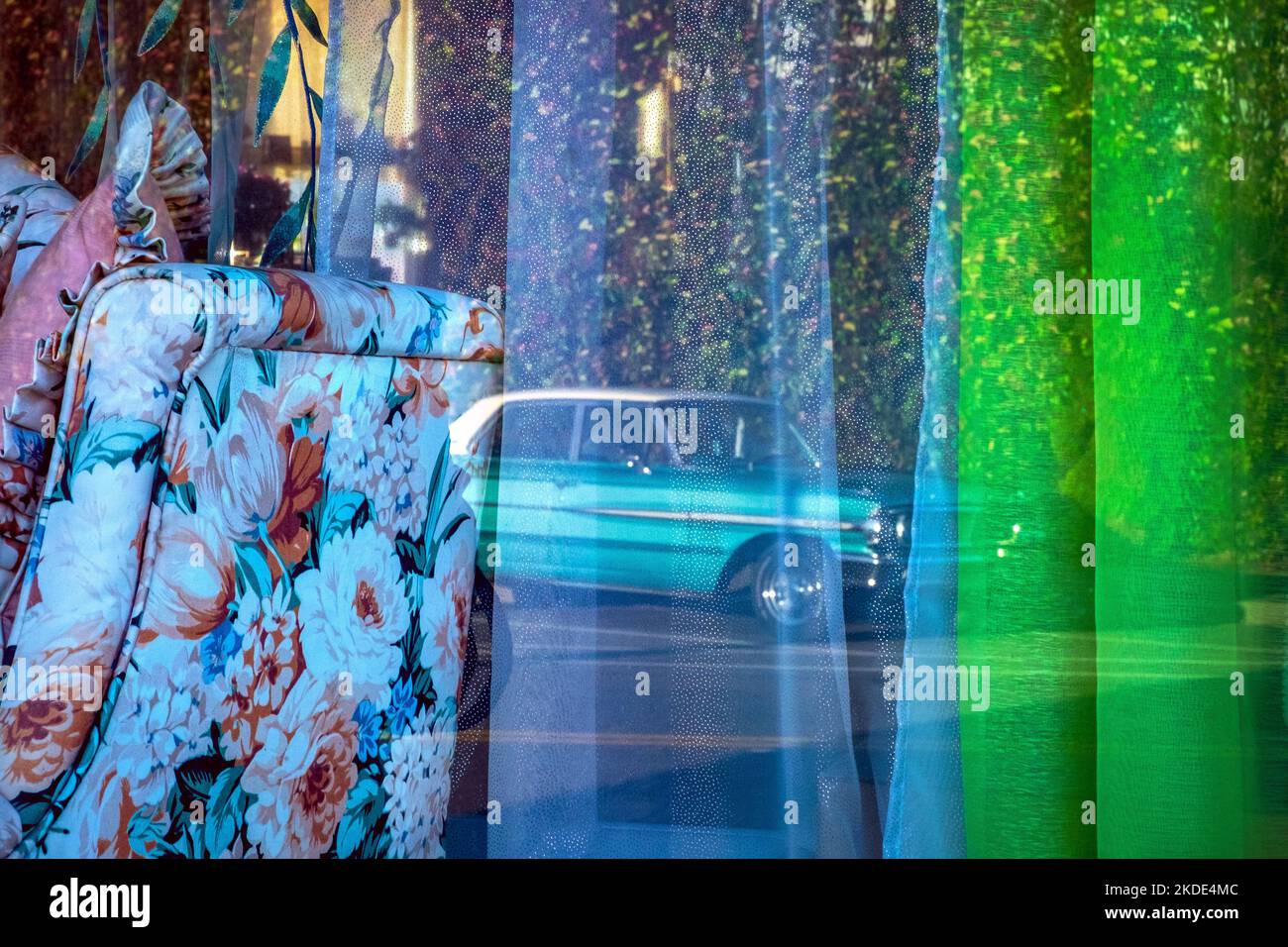Classic turquoise car reflected in colorful fabric or curtains in a window Stock Photo