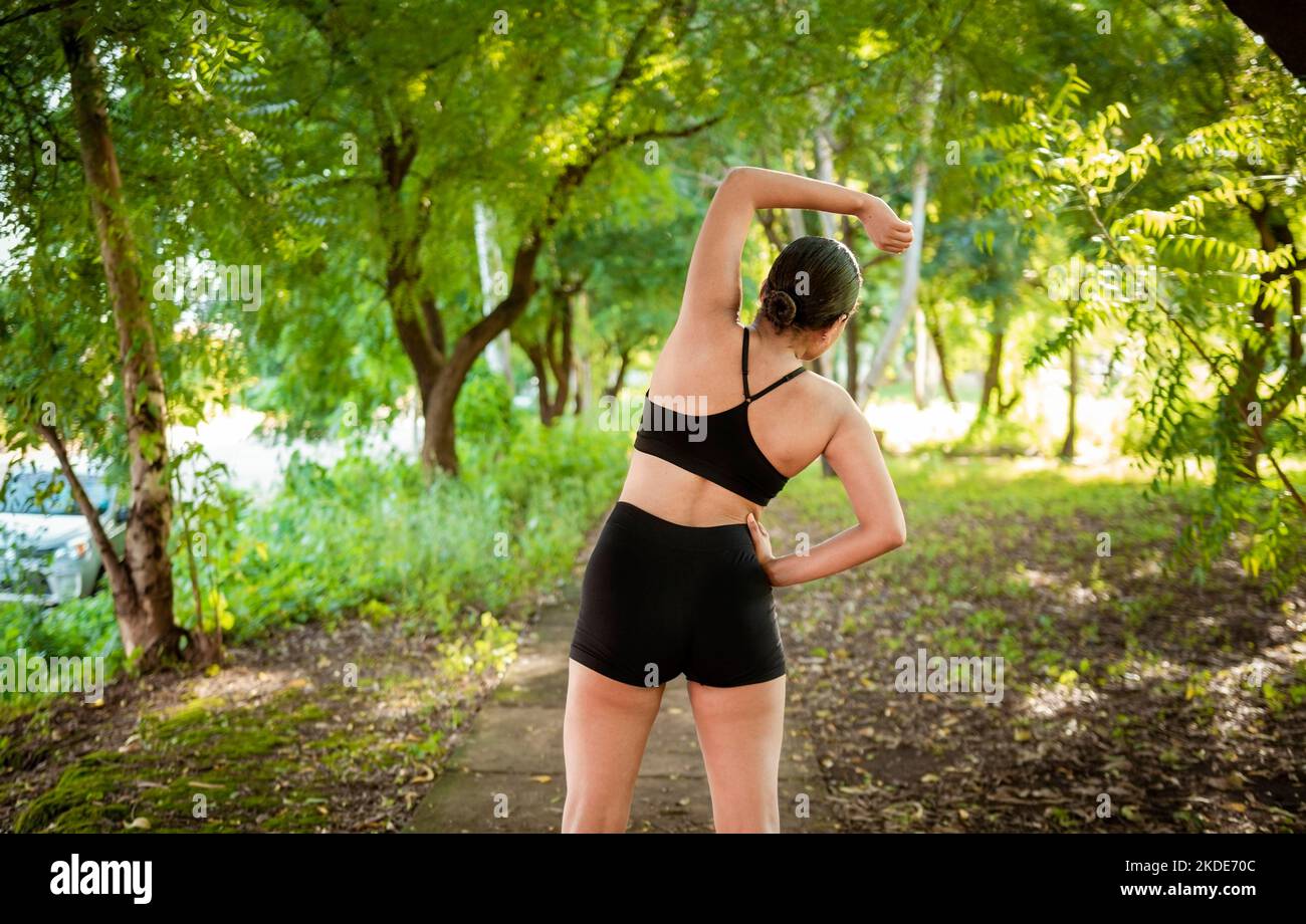 Athlete girl doing warmup exercises in a park. Sporty woman doing