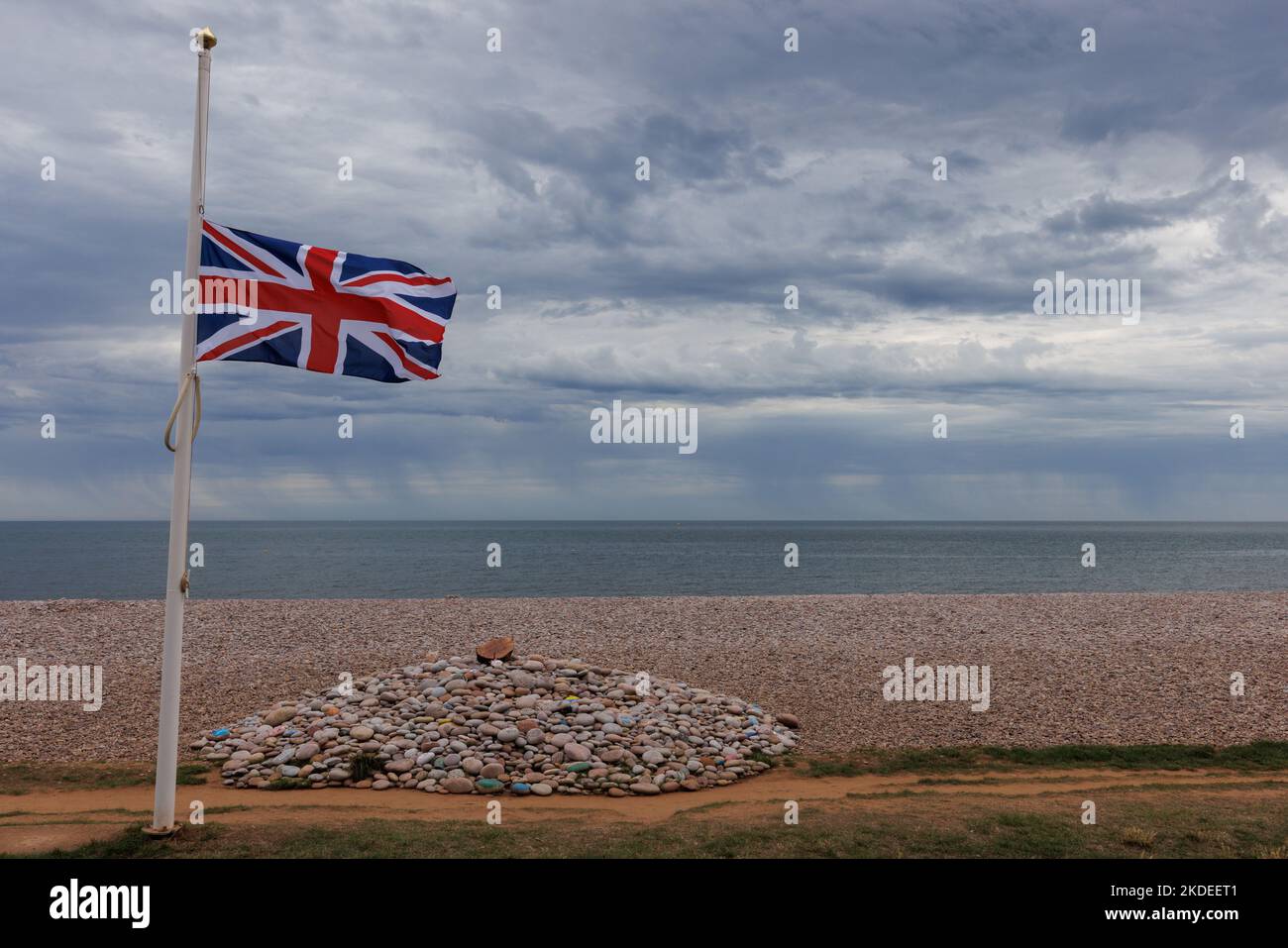 Commemoration cairn on beach with Union Jack flag at half mast