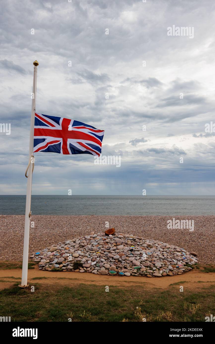 Commemoration cairn on beach with Union Jack flag at half mast