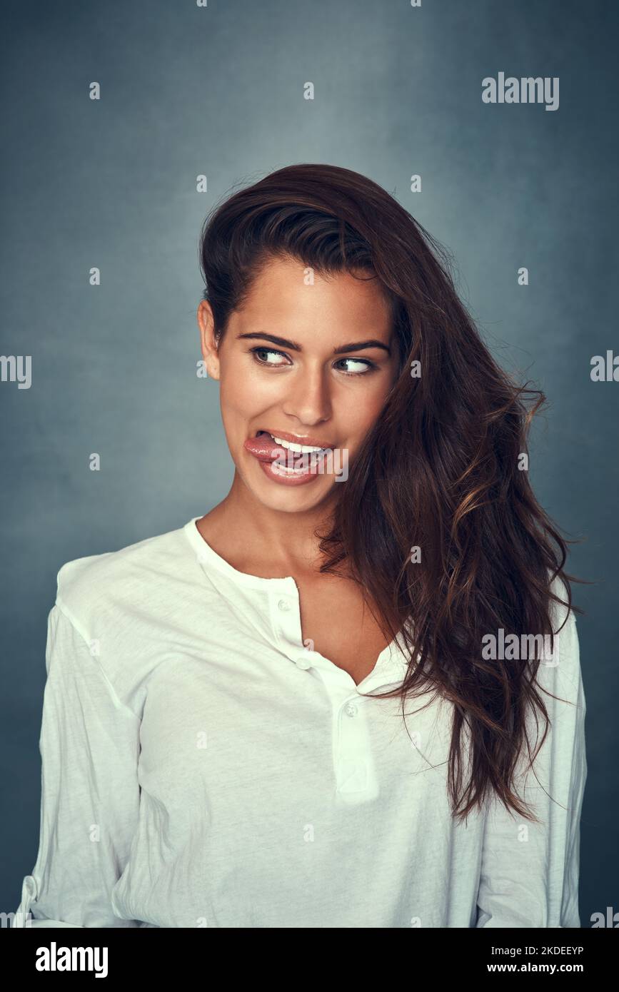 Embrace your silly side. a beautiful young woman pulling a funny face against a gray background in studio. Stock Photo