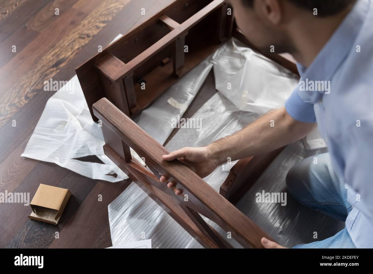 Cropped view young handy man assembling parts of wooden table Stock Photo