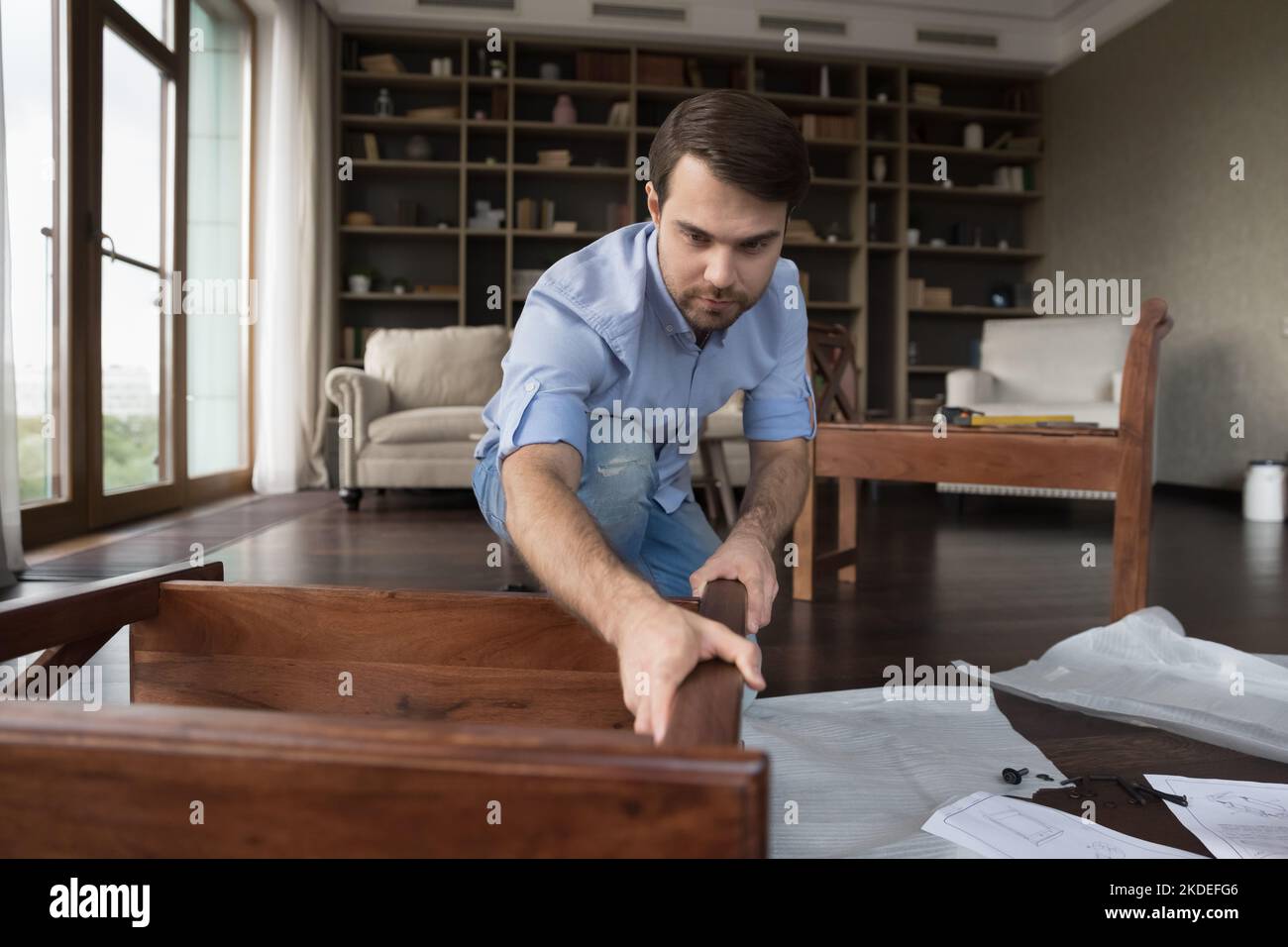 Millennial single handyman assembles furniture alone at home Stock Photo