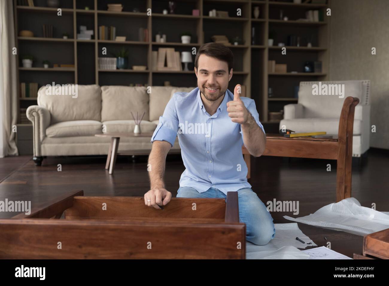 Man showing thumb up after assembling wooden table Stock Photo
