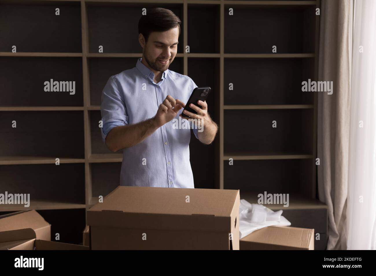 Young man using smartphone on relocation day Stock Photo