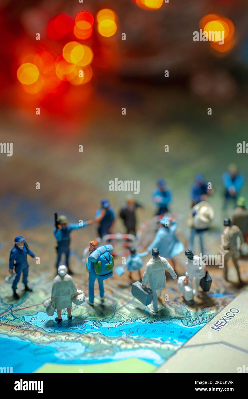 Miniature toy people concept US border patrols against a group of migrant from Mexico-blur bokeh light in the background. Stock Photo