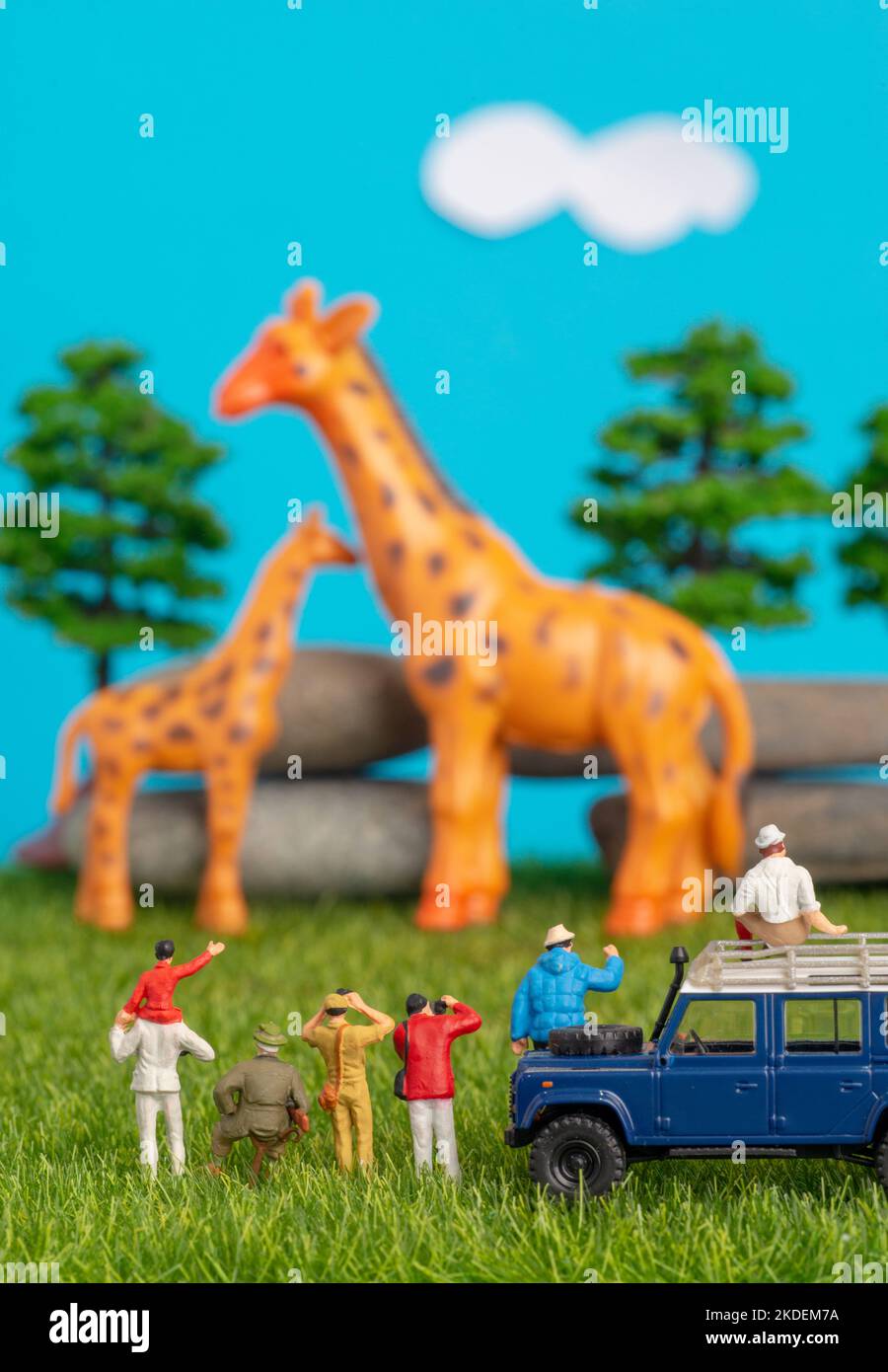 Miniature toys of a group of people on safari trip watching giraffes