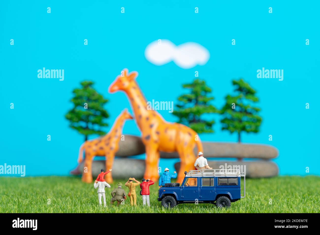 Miniature toys of a group of people on safari trip watching giraffes