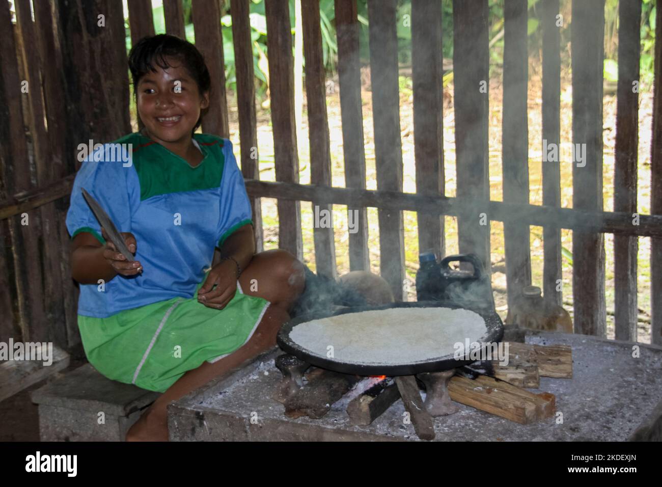 Woman demonstrates preparing and cooking yucca root tortillas in an indoors kitchen in a Siona village in the Cuyabeno Wildlife Reserve, Ecuador. Stock Photo