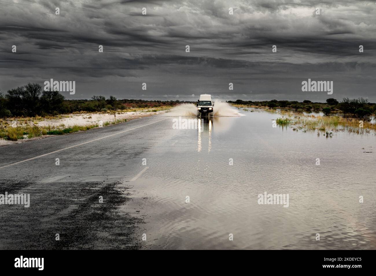 Car driving on a flooded road in Australia's Outback. Stock Photo