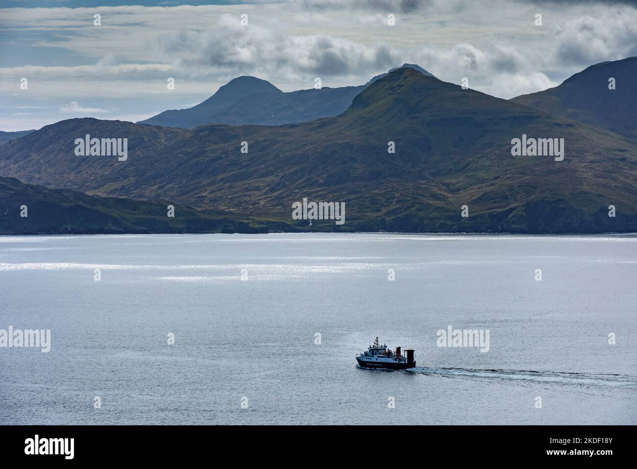 The Caledonian MacBrayne Small Isles ferry, the MV Lochnevis, leaving the harbour, Isle of Canna, Scotland, UK.  The mountains of Rum behind. Stock Photo