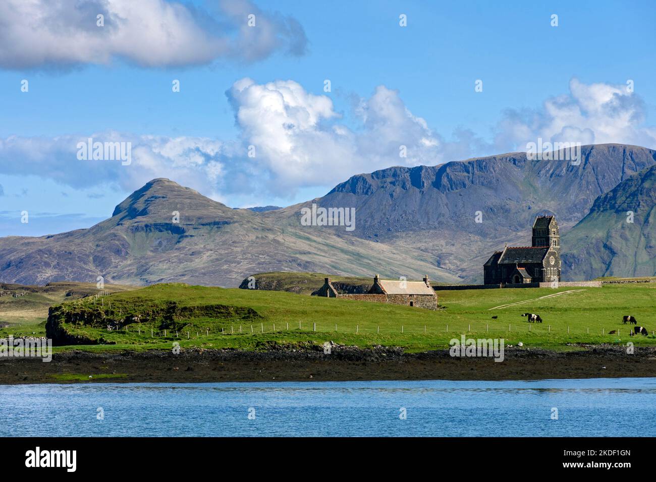 The former church of St. Edward on the isle of Sanday, from the Isle of Canna, Scotland, UK.  Behind are the mountains of the Isle of Rum. Stock Photo