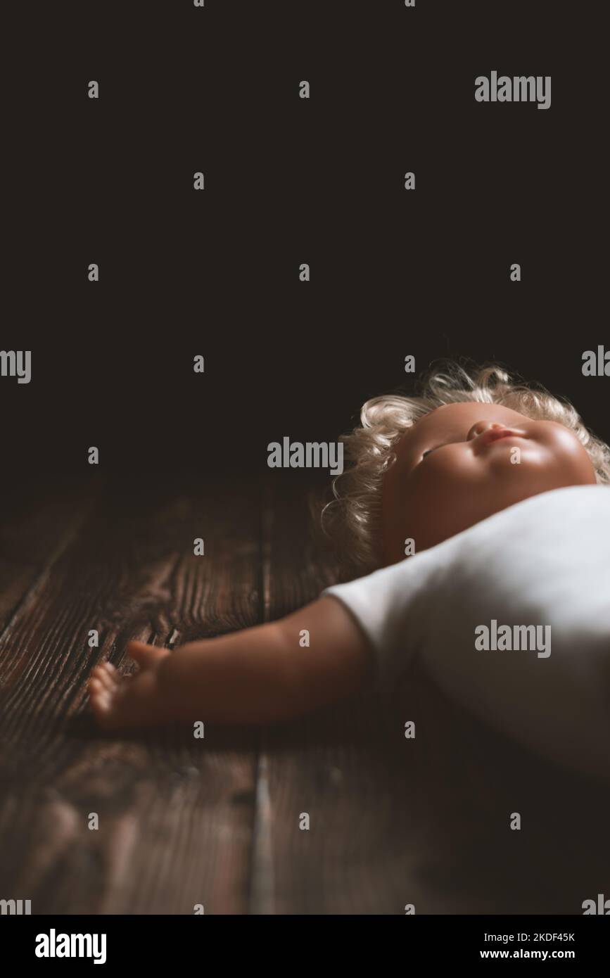 Lost old blonde toy doll with closed eyes lying on the floor Stock Photo