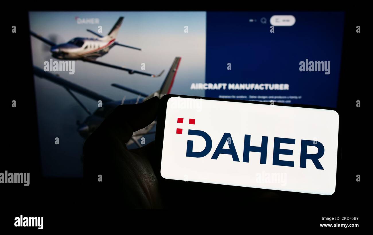 Person holding cellphone with logo of French aerospace company Daher Group on screen in front of business webpage. Focus on phone display. Stock Photo